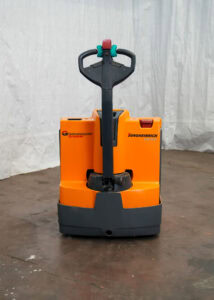 Ein orange-grauer Hubwagen mit Hebel, steht offenbar in einer Lagerhalle.